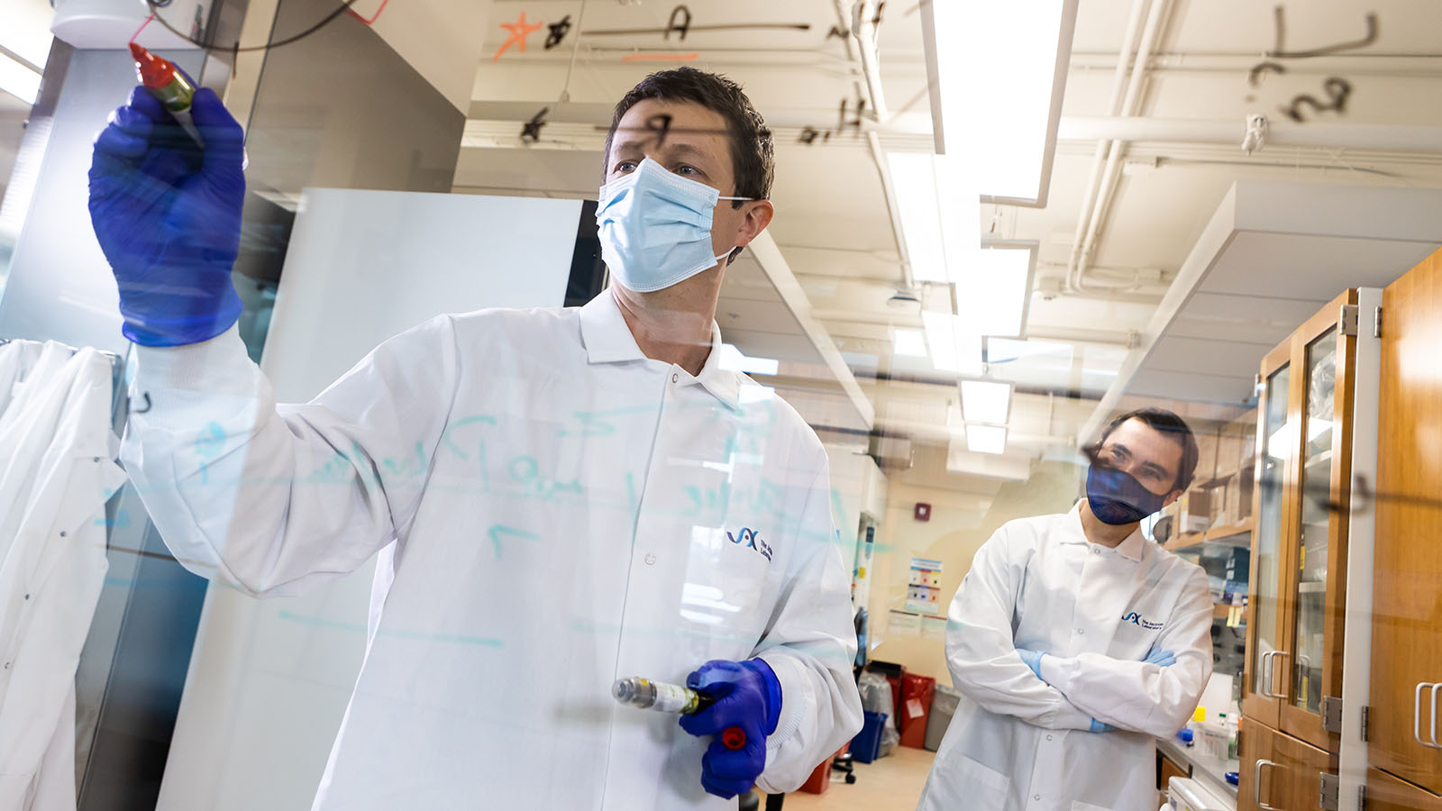 The Jackson Laboratory's Ryan Tewhey standing at a board with his staff. Photo credit: Tiffany Laufer